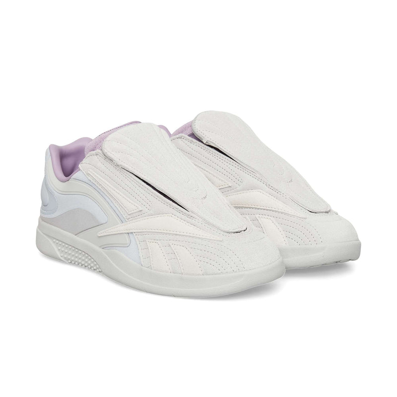 The Reebok Hammer Pro Ltd features light beige and lavender suede uppers with covered laces, a modern sporty design, and a flat durable rubber sole.