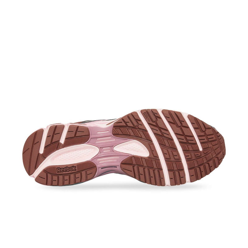 The image displays the sole of the Reebok Premier Road Ultra, featuring a brown, textured pattern with light pink accents and a visible heel logo. Its dual-density midsole offers enhanced support for athletic use.