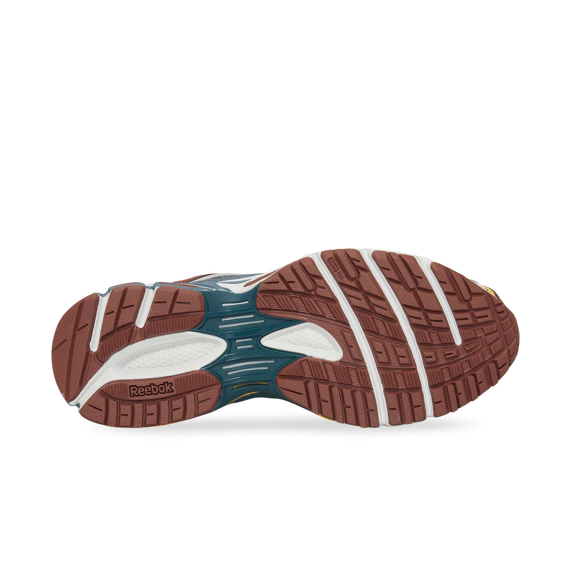 The image displays the sole of the Reebok Premier Road Ultra, featuring a brown and white tread pattern for traction and support. A dual-density midsole and the Reebok logo are visible near the heel on the side of the sole.
