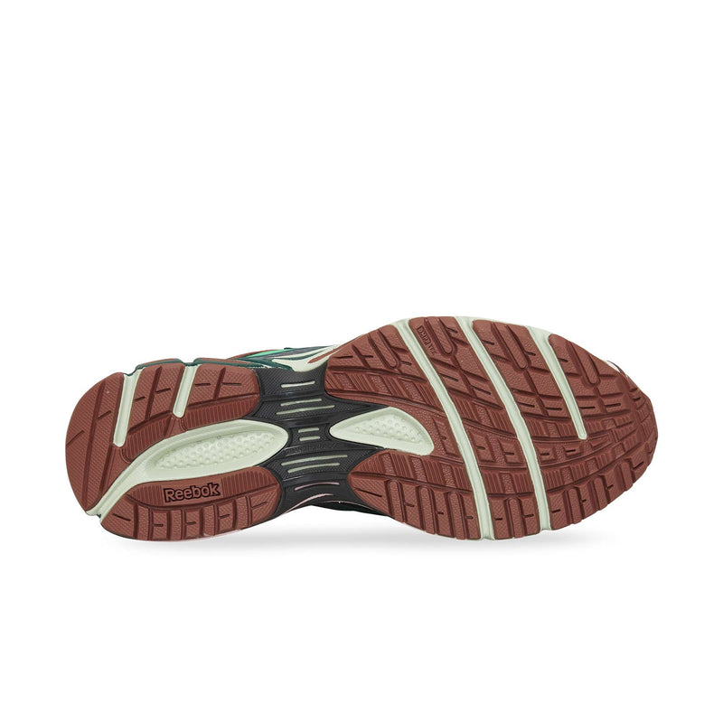 The image displays the sole of the Reebok Premier Road Ultra sneaker, featuring a brown and off-white traction pattern with visible Reebok branding and textured grooves for enhanced grip.