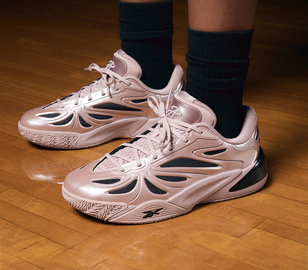 Pink sneakers with black accents worn indoors on a wooden floor