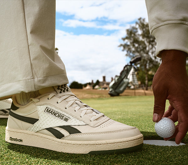 MAN TOUCHING GOLF BALL WEARING WHITE REEBOK SHOES