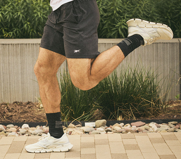 Person running outdoors with Reebok shoes and shorts