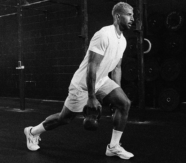 Person performing a kettlebell exercise in a gym setting