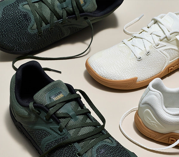 Two pairs of sneakers, one green and black, the other white with brown soles, on a light background.