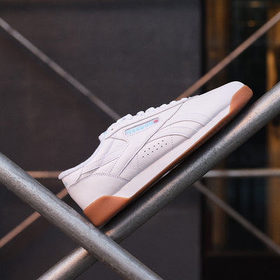 White sneaker with brown accents on a metal surface