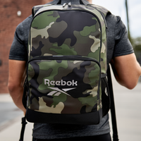 Person wearing a Reebok camouflage backpack on a street.